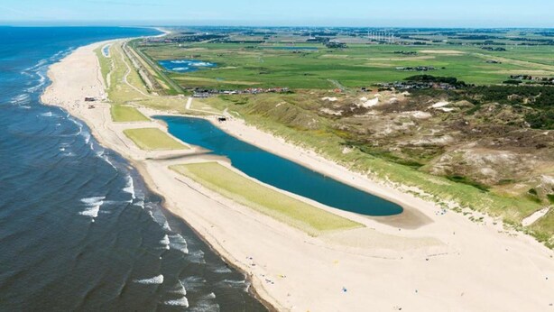 An aerial view of a coastal area with a beach, a large water body, and green fields. - Apartment With Dunes View of Petten (Petten)