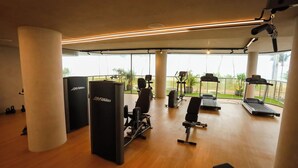 A gym with cardio equipment, weight machines, and a bench. - Setai Yacht Comfort - By Almare Flats (Joao Pessoa)