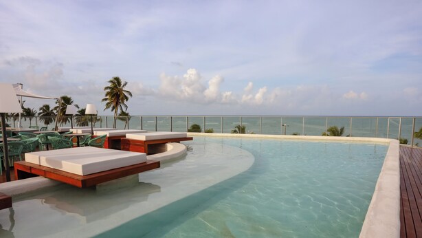 A pool area with lounge chairs and a wooden deck, overlooking a beach. - Setai Yacht Comfort - By Almare Flats (Joao Pessoa)