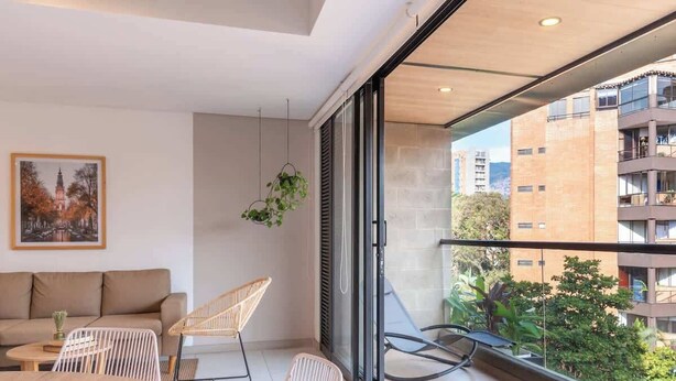 A modern apartment with a balcony, a sofa, and a dining table. - NOK Bright 3BR with terrace in Laureles Medellin (Medellín)