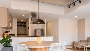 A modern kitchen with a central island, white wire chairs, and a hanging pendant light. - NOK Bright 3BR with terrace in Laureles Medellin (Medellín)
