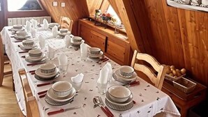 Un comedor con una mesa larga dispuesta para una comida, paredes de madera, un reloj y un cuadro de un oso polar.