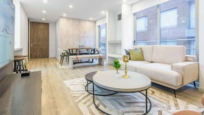 Una sala de estar moderna con un sofá, una mesa de centro redonda y un comedor con mesa y sillas.