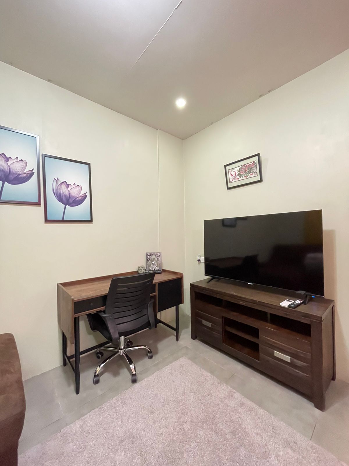 A room with a desk, chair, TV, and artwork on the walls.