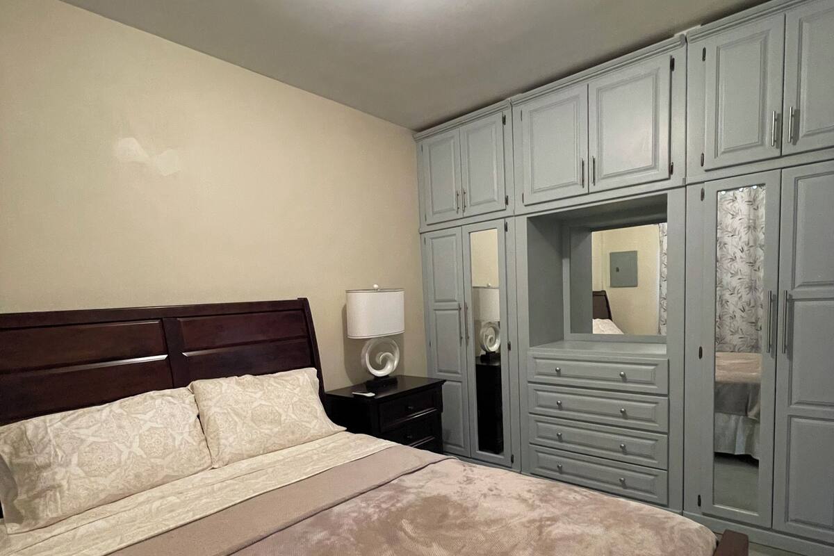 A bedroom with a bed, nightstand, dresser, and wardrobe.