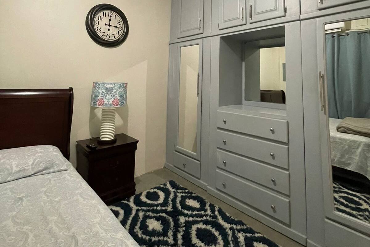 A bedroom with a bed, a dresser, a mirror, and a clock on the wall.