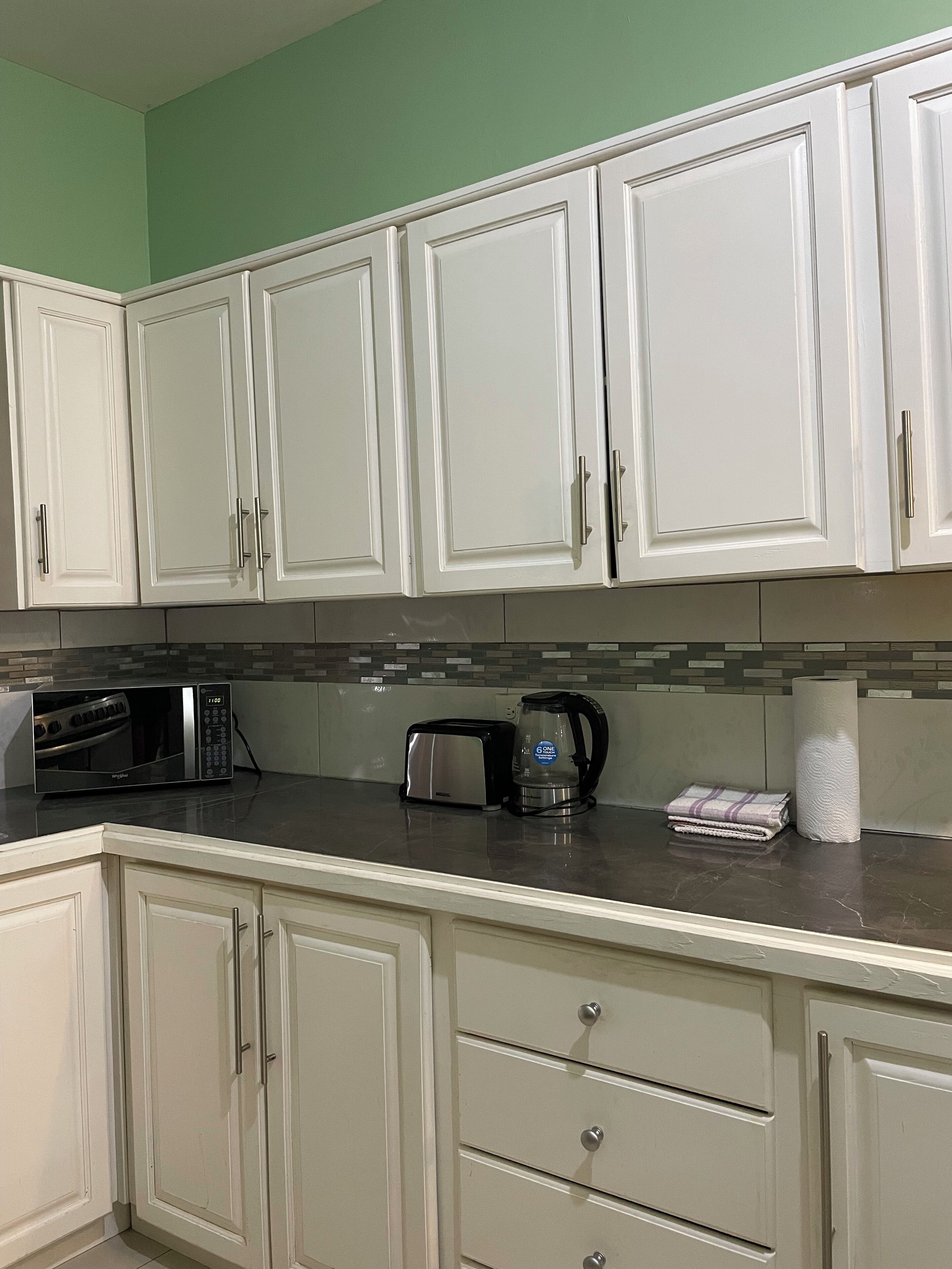 A kitchen with white cabinets, a microwave, toaster, and a coffee maker.