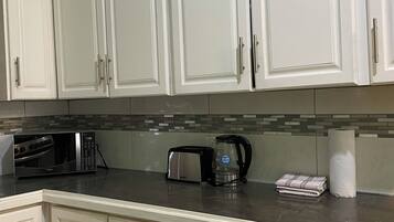 A kitchen with white cabinets, a microwave, toaster, and a coffee maker.