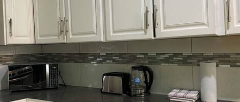 A kitchen with white cabinets, a microwave, toaster, and a coffee maker.