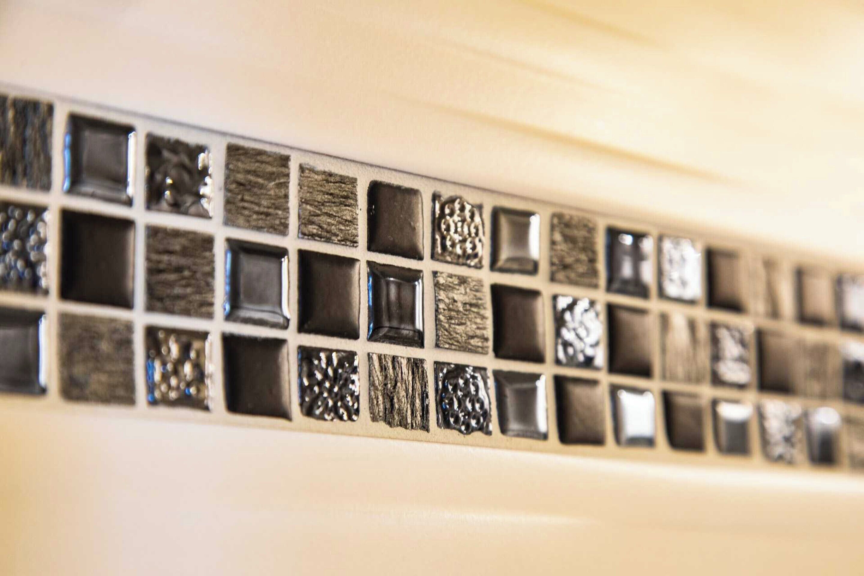 Primer plano de un salpicadero de baño con distintos azulejos texturizados.