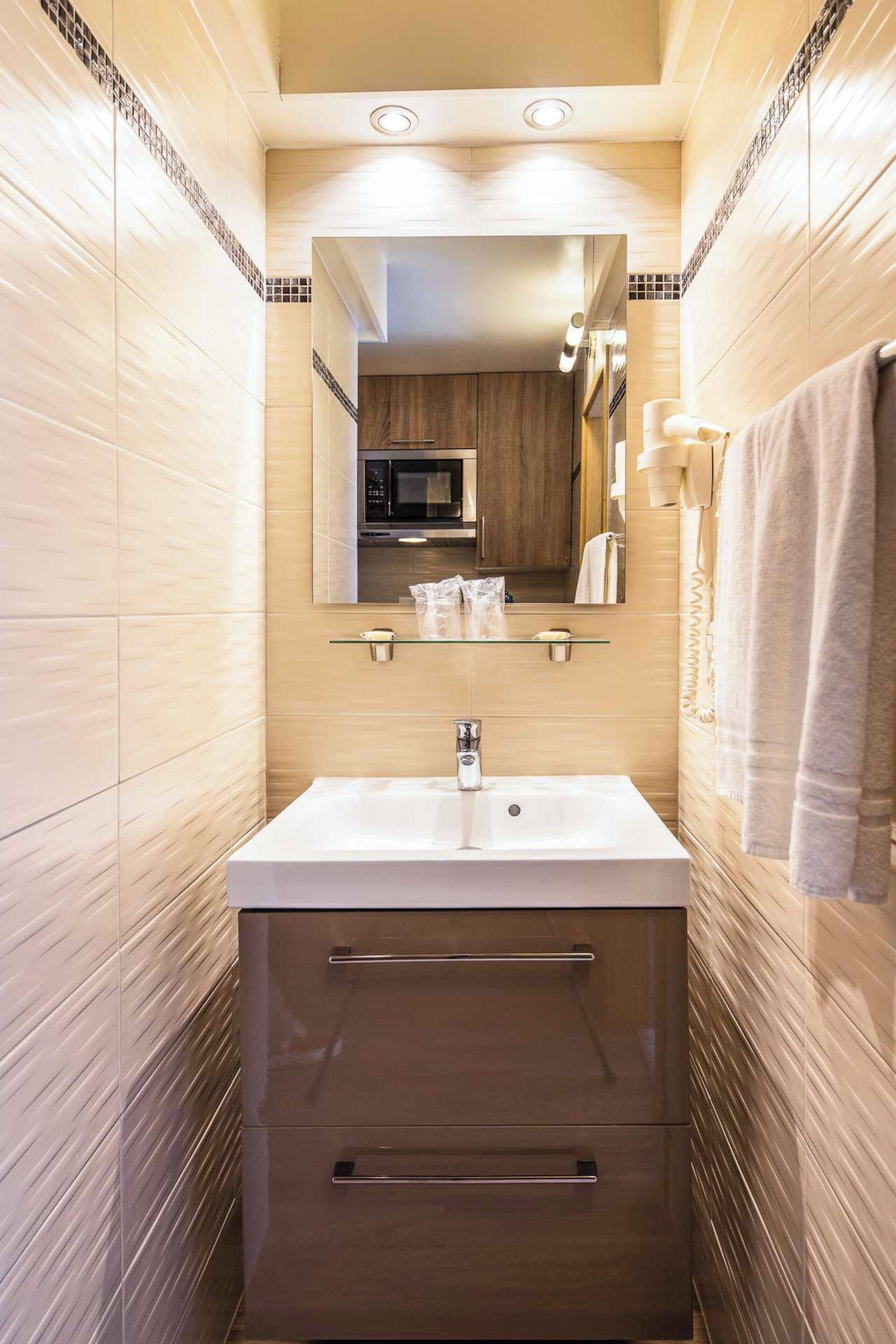 A modern bathroom with a large mirror, a sink, and a cabinet.