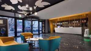 A hotel lobby with teal and yellow seating, a reception desk, and a modern ceiling design. - Aimeite Boutique Hotel (Changyuan)