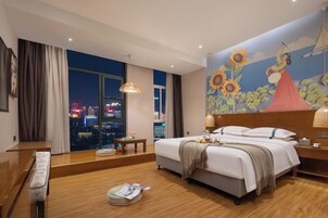 Habitación de hotel con un ventanal grande, una cama, una mesita de noche y un mural en la pared.