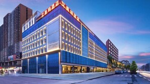 A modern hotel with a glass facade, multiple floors, and a prominent entrance. - Aimeite Boutique Hotel (Changyuan)