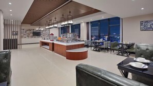 A modern hotel lobby with a central bar area, seating arrangements, and large windows offering a view of the cityscape. - Aimeite Boutique Hotel (Changyuan)