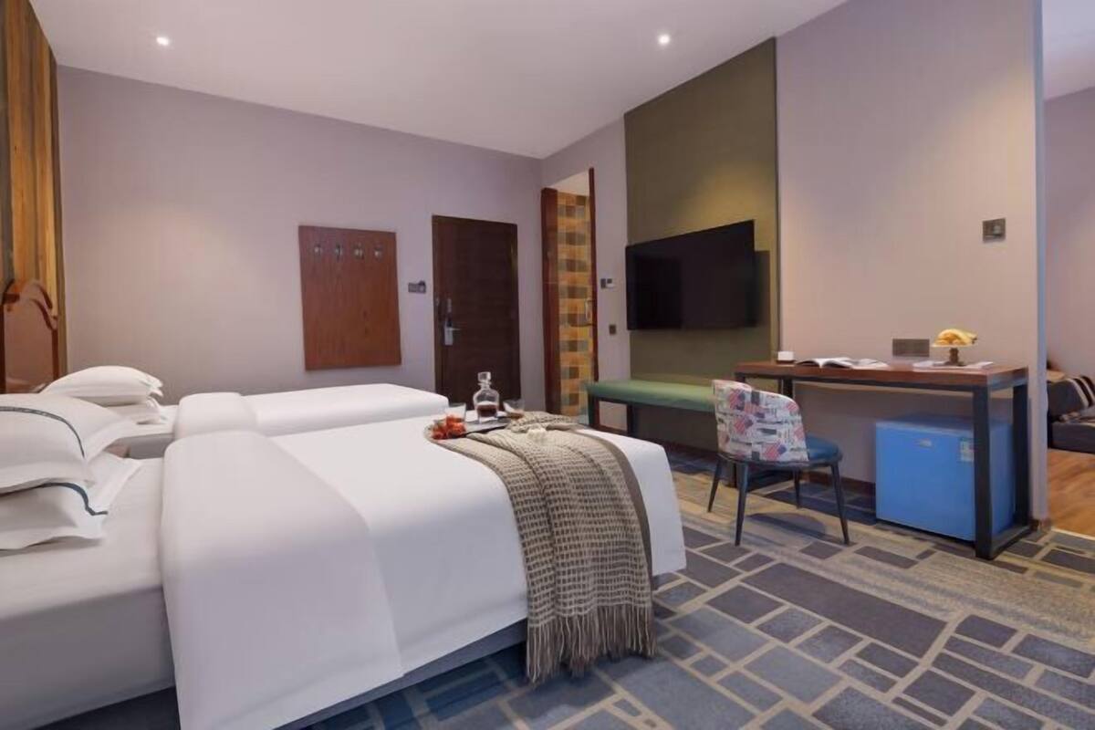 A hotel room with a bed, a desk, a chair, a television, and a small refrigerator.