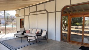 Ein überdachter Patio-Bereich mit einer Couch, einem Couchtisch und Sesseln.