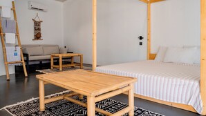 Une pièce comprenant un lit, une petite table, un canapé, un élément de décoration suspendu et une échelle.