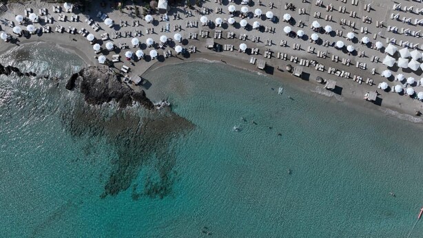 Vue aérienne d’une plage avec des rangées de transats et de parasols.