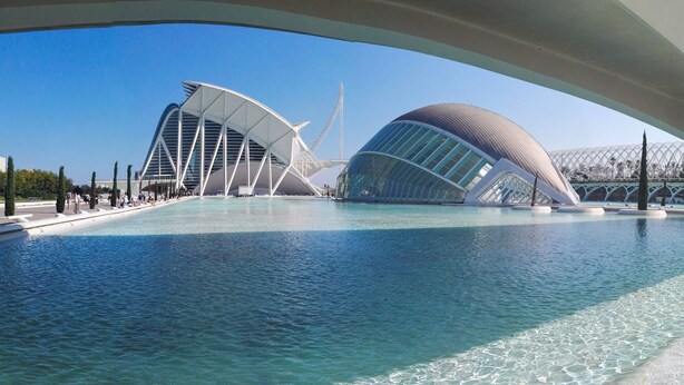 A modern architectural structure with a large water body in front.