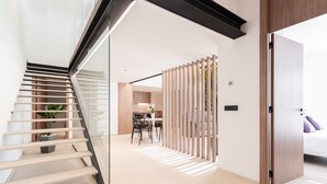 A modern interior with a staircase, a dining area, and a bedroom.
