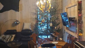 A cozy living room with a wooden ceiling, a Christmas tree, a fireplace, and a mounted television. - Muskoka Cabin, Vacation home rental, Muskoka cottage, Bear Den Muskoka, cottage (Bracebridge)