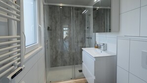 A modern bathroom with a glass shower enclosure, a white sink, and a mirror above the vanity. - Wellness Lodge Hottub on the Salland Ridge in Hellendoorn (Haarle)