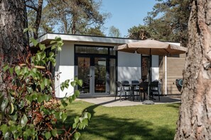 Ein modernes Haus mit Terrasse, Sitzgelegenheiten im Freien und einem überdachten Bereich.