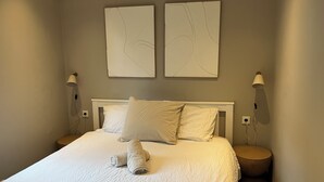A bedroom with a bed, two wall-mounted lamps, and two abstract wall art pieces. - Wellness Lodge Hottub on the Salland Ridge in Hellendoorn (Haarle)