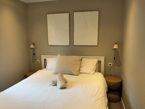 Ein Schlafzimmer mit einem Bett, zwei Wandleuchten und zwei abstrakten Kunstwerken an der Wand.