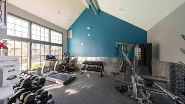 Une salle de sport  équipée de matériel d’exercice, d’un tapis de course et d’haltères.