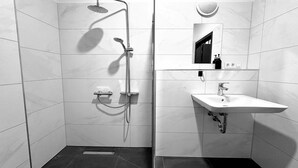 A modern bathroom with a shower, sink, and mirror. - Hotel FFA 62 (Berlin)