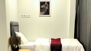 A bedroom with a bed, nightstand, chair, and a small table. - Hotel FFA 62 (Berlin)