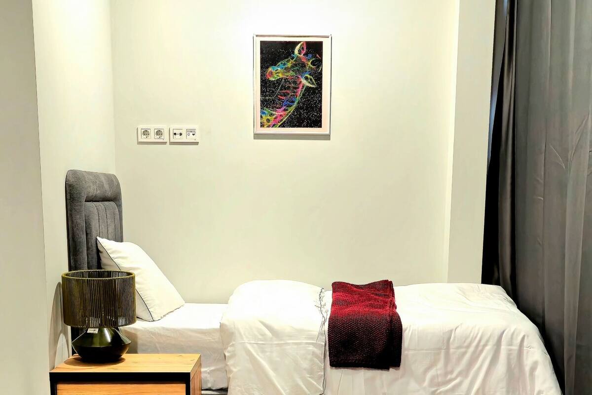 A bedroom with a bed, nightstand, chair, and a small table.