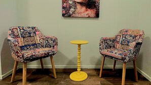 Two patterned armchairs, a small yellow table, and a colorful painting on the wall. - Hotel FFA 62 (Berlin)