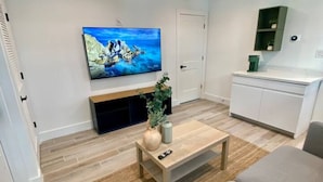 Un salon moderne avec un téléviseur à écran plat, une table basse et un canapé.
