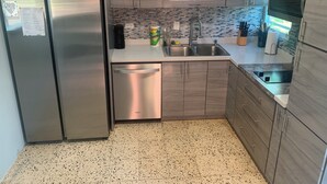 Una cocina moderna con electrodomésticos de acero inoxidable, salpicadero de azulejos y armarios de madera.