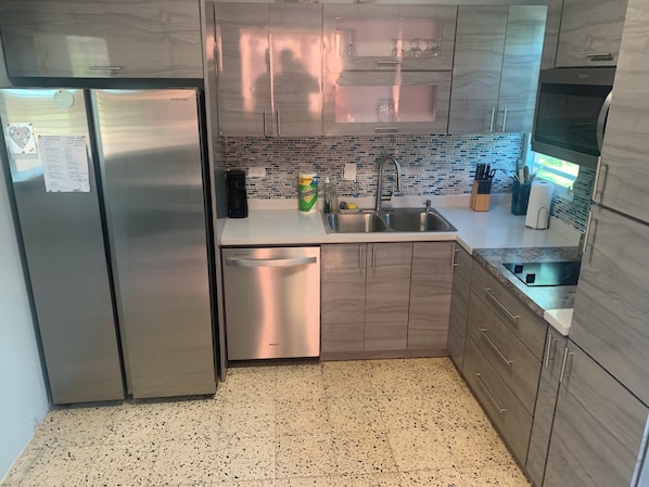 Una cocina moderna con electrodomésticos de acero inoxidable, salpicadero de azulejos y armarios de madera.