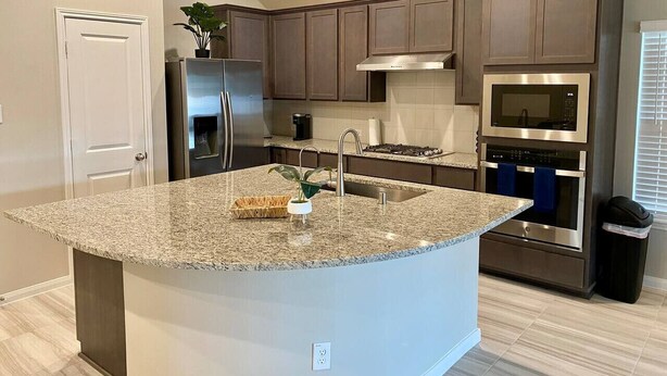 A modern kitchen with granite countertops, stainless steel appliances, and dark wooden cabinets. - 4-BR Getaway Ideal for Families (Richmond)