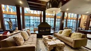 A spacious living room with two sofas, a fireplace, and large windows offering a city view.