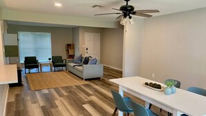 A modern living room with a sofa, chairs, a dining table, and a ceiling fan. - 3 BR Getaway Ideal for Families (Houston)