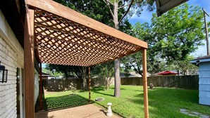 A backyard with a wooden pergola, a patio area, and a lawn. - 3 BR Getaway Ideal for Families (Houston)