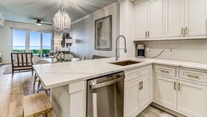 A modern kitchen with a large island, white cabinetry, and a view to the outside.