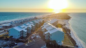 A coastal hotel with multiple buildings, a parking area, and a beach view. - Coastal Serenity  - Waterfront - Heated Pool - Best spot on the beach. (Pensacola Beach)