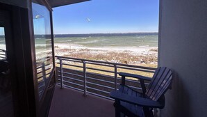 A balcony with a view of the beach and ocean, featuring a chair and a railing. - Coastal Serenity  - Waterfront - Heated Pool - Best spot on the beach. (Pensacola Beach)