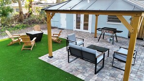 Un espace patio aménagé avec du mobilier d’extérieur, un barbecue et un coin salon abrité.