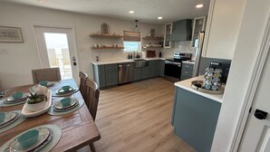 Eine moderne Küche mit Holzboden, eingebauten Geräten und einer Essecke mit einem Holztisch für vier Personen.