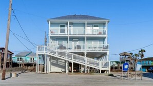 Ein mehrstöckiges Gebäude direkt am Strand mit einer zentralen Treppe und Balkonen.