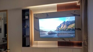Una sala de estar moderna con un televisor de pantalla plana grande montado en una pared con diseño tipo mármol.