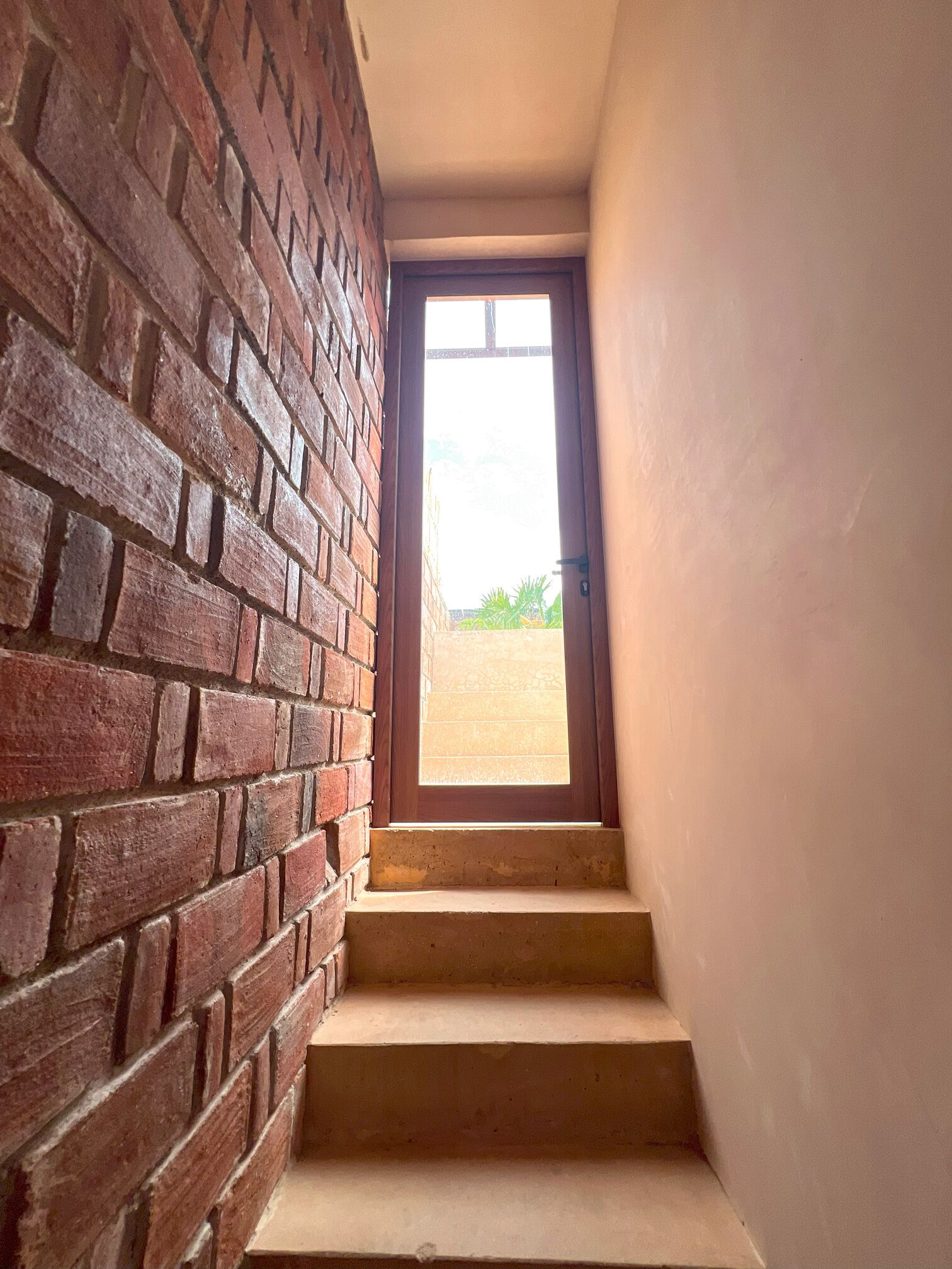 A staircase leading to a door with a view of a courtyard.